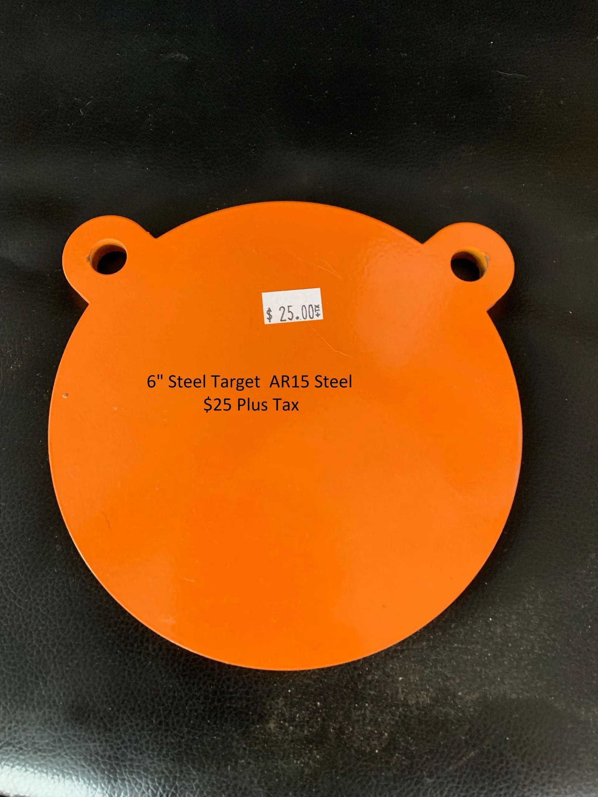 An orange target with holes in it is sitting on a black surface