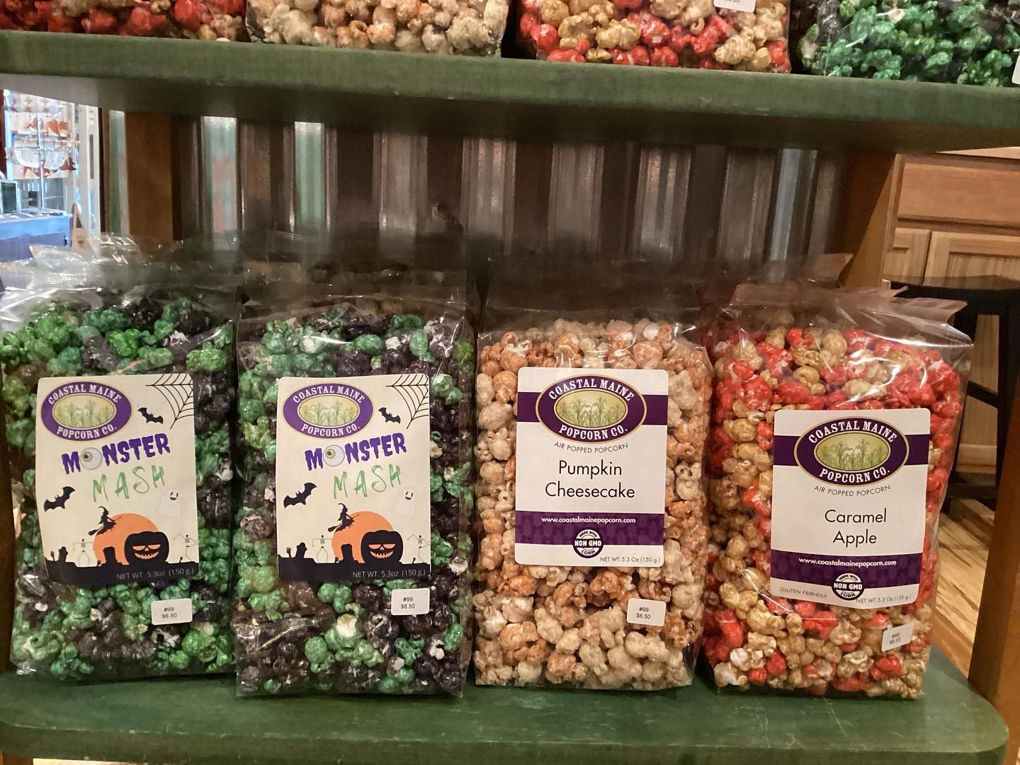 Four bags of popcorn are lined up on a shelf.