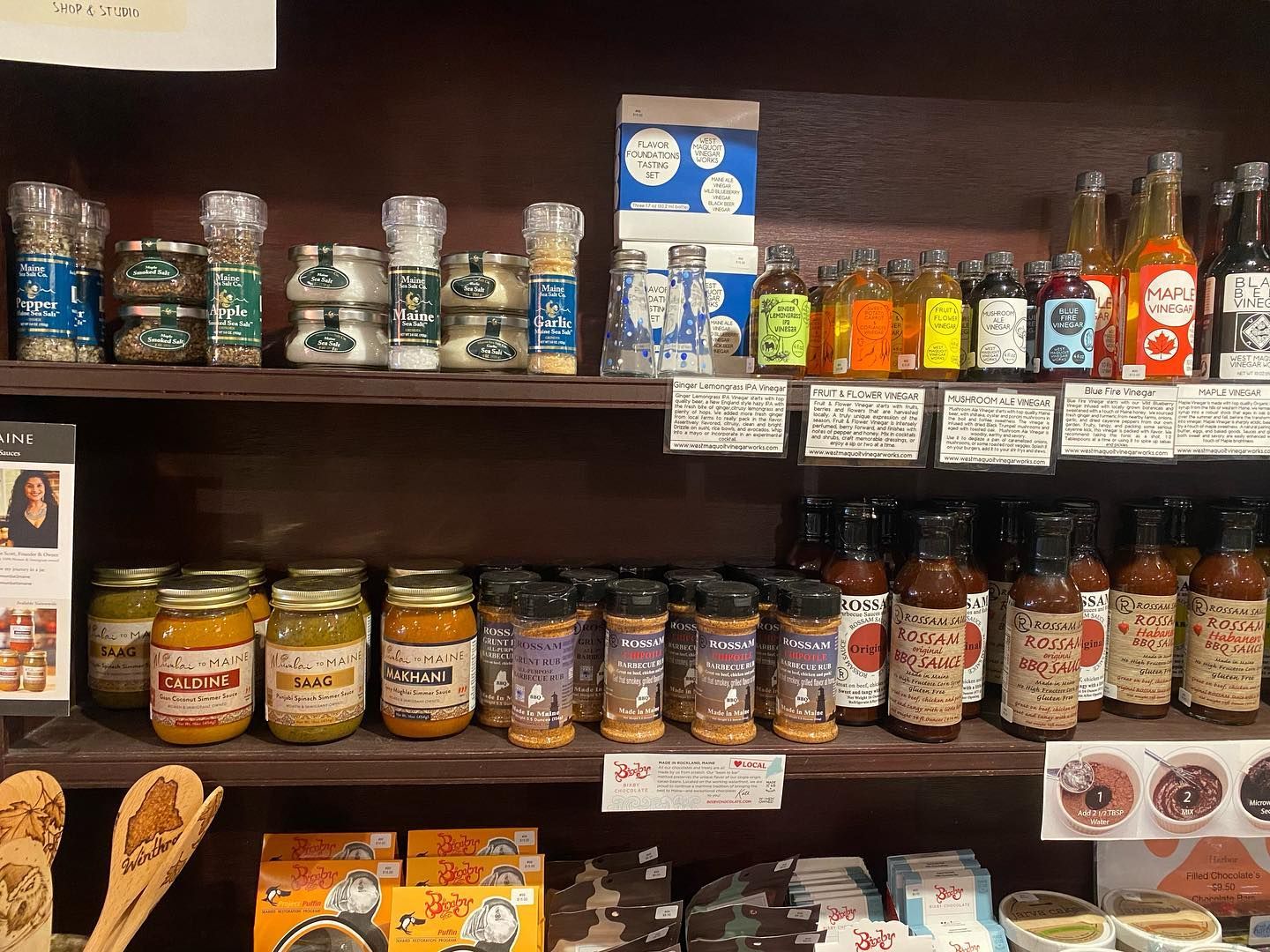 A shelf filled with jars , bottles , and condiments.
