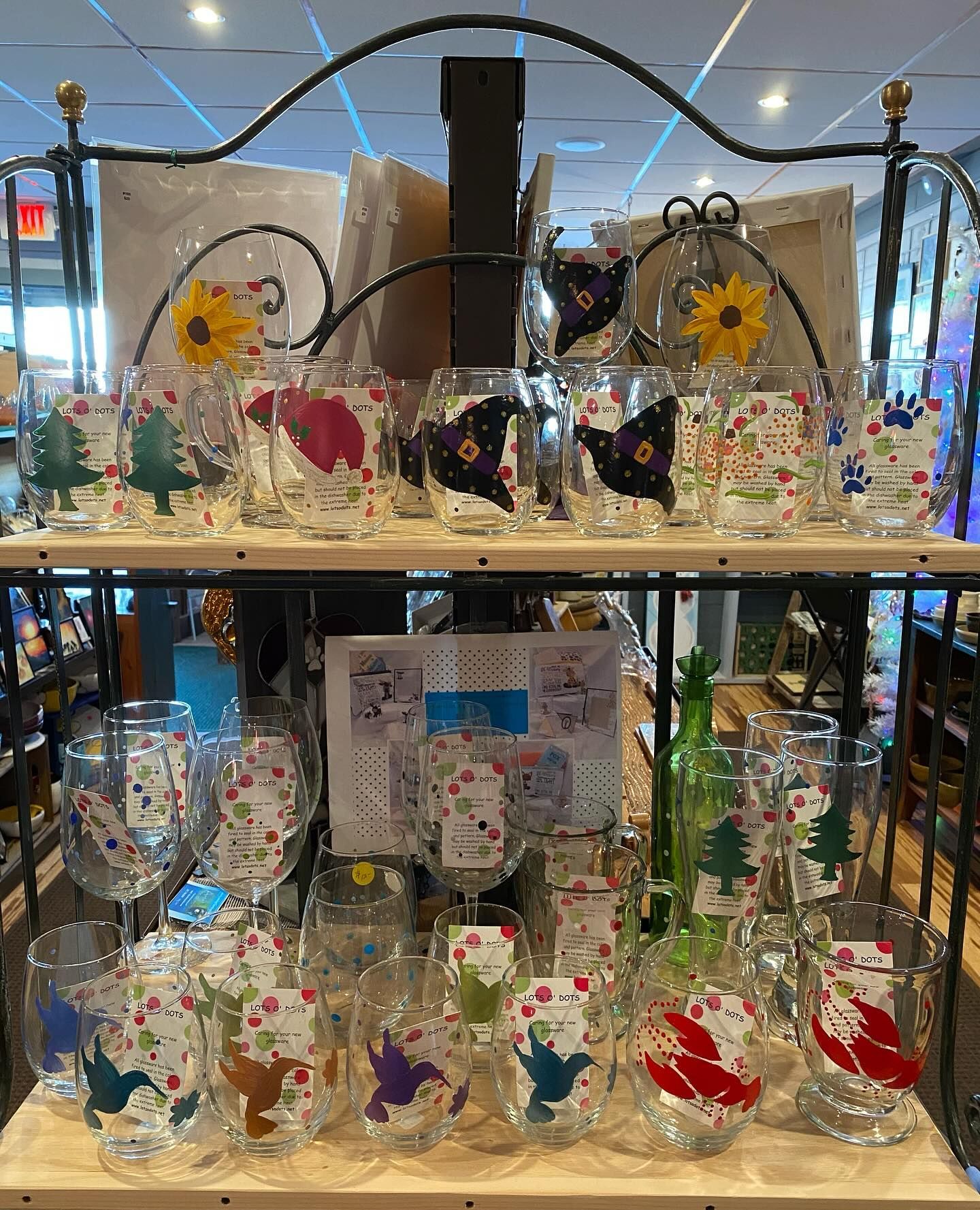 A shelf filled with wine glasses with different designs on them.