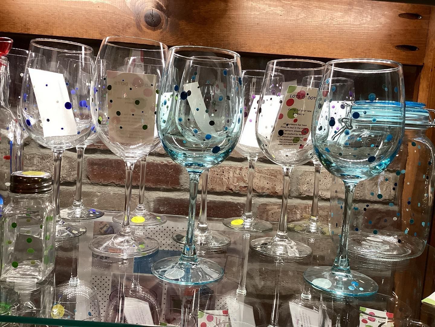 A row of wine glasses are lined up on a glass shelf.