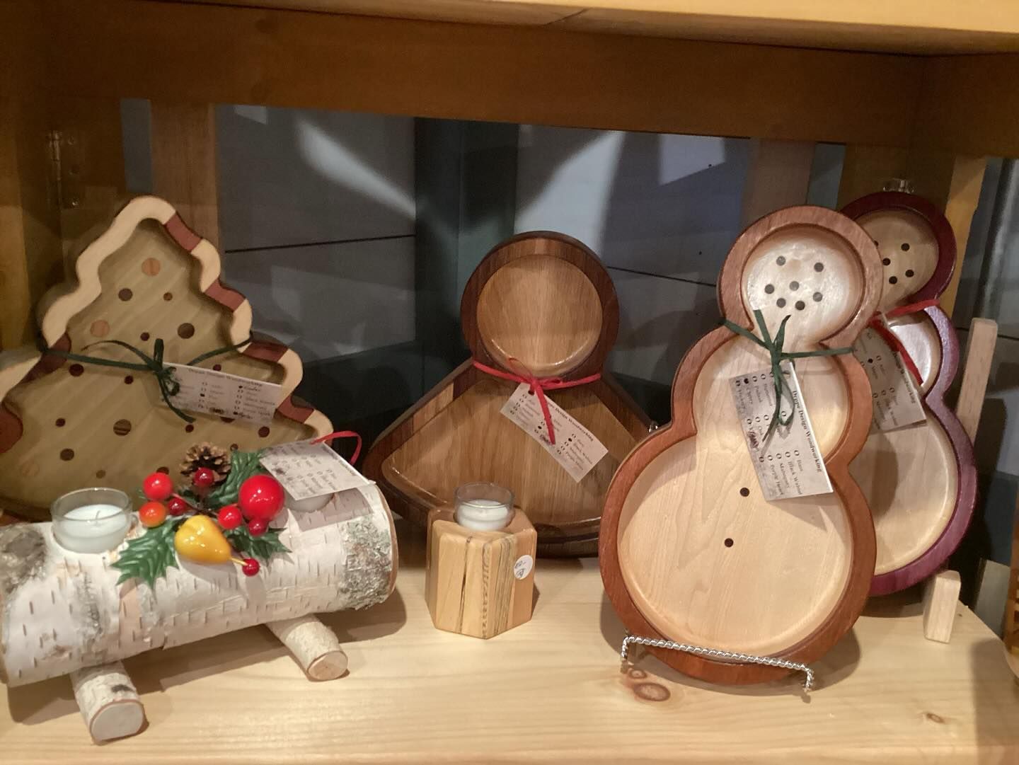 A display of wooden christmas decorations on a wooden shelf.