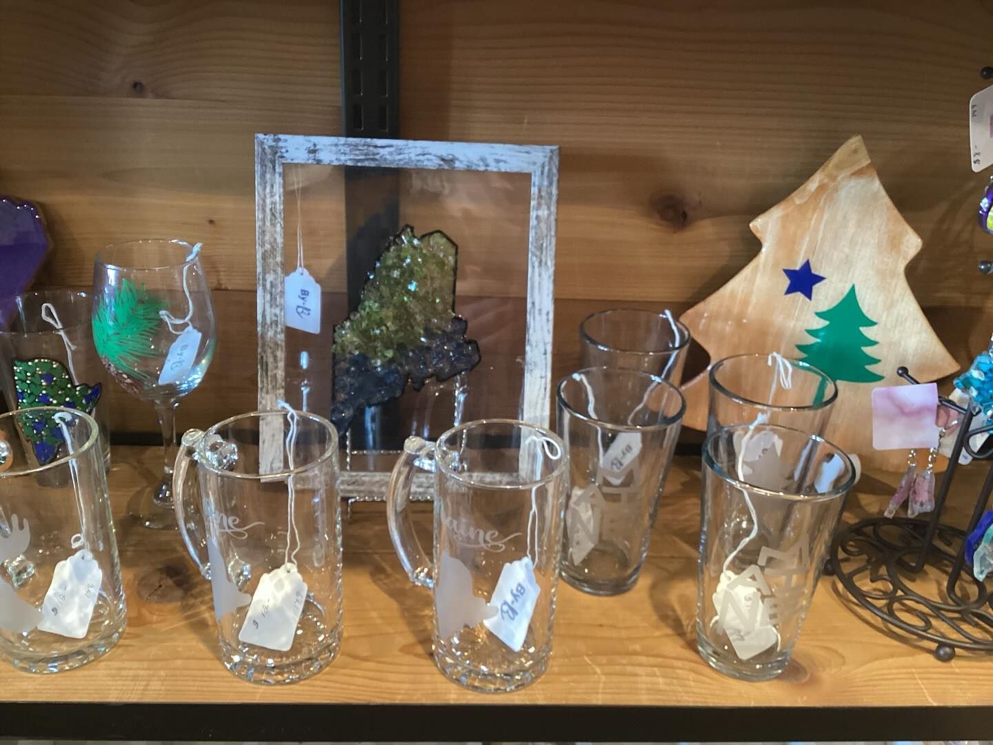 A shelf filled with glasses and a picture of a christmas tree.