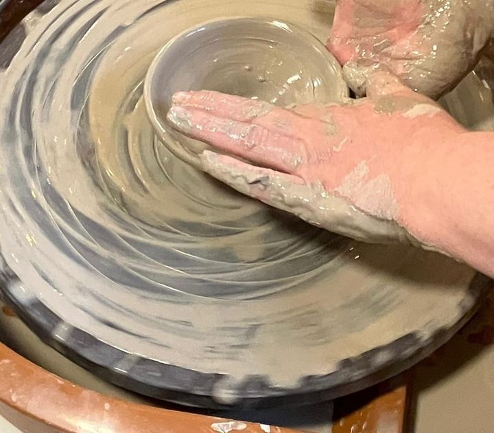 A person is making a bowl on a pottery wheel.