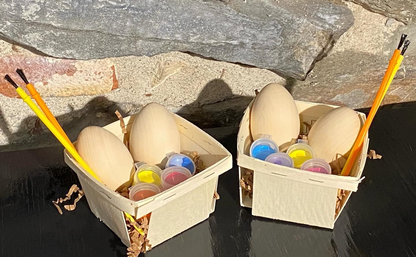 Two baskets filled with eggs and paint are sitting on a table.