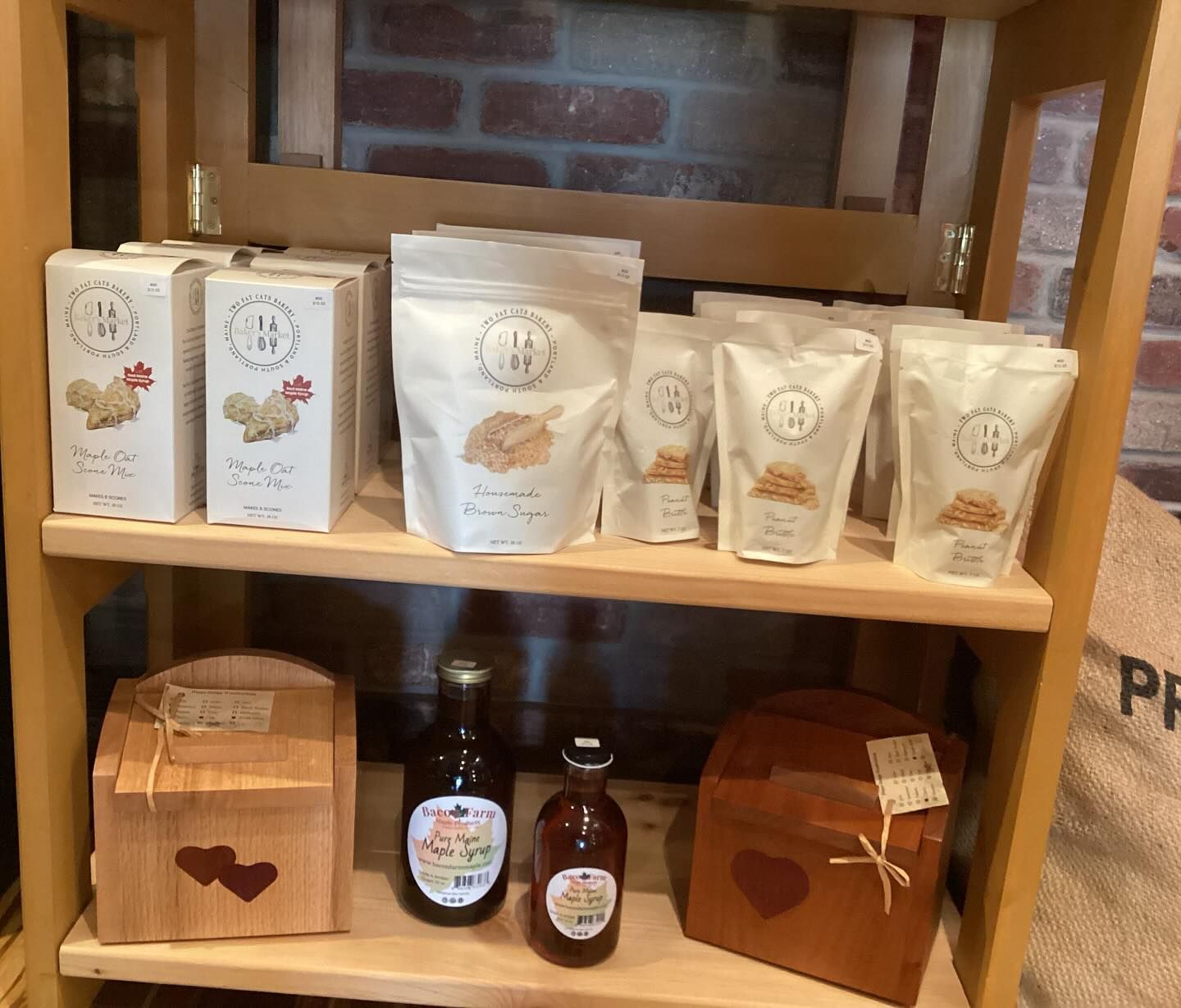 A wooden shelf with bags of food and a bottle of syrup