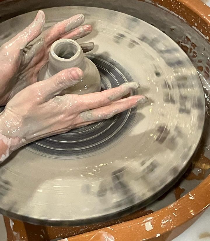 A person is making a vase on a pottery wheel.