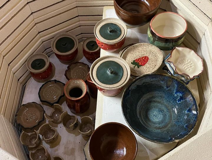 A group of bowls and plates are sitting inside of a kiln.