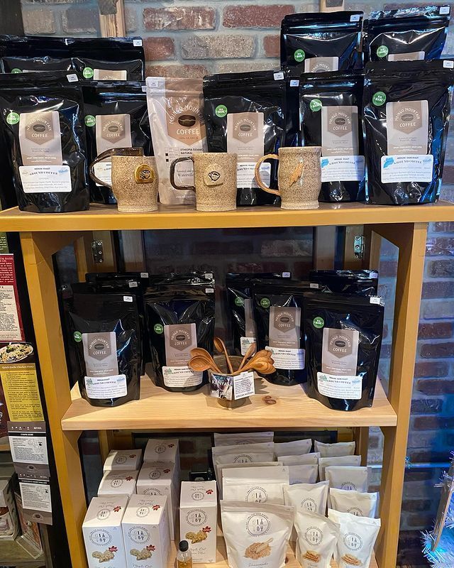 A shelf filled with bags of coffee and mugs.