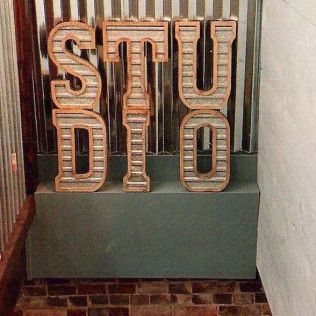 A sign that says studio is sitting on a brick wall.