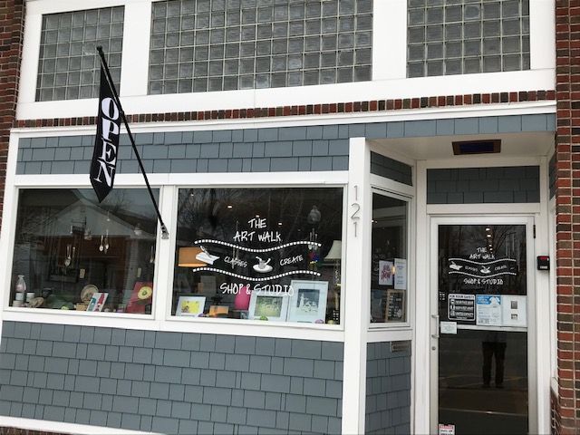 A store front with a flag that says ' art walk ' on it