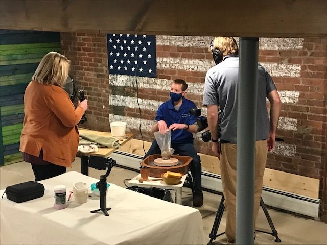 A group of people are standing around a table in front of an american flag.