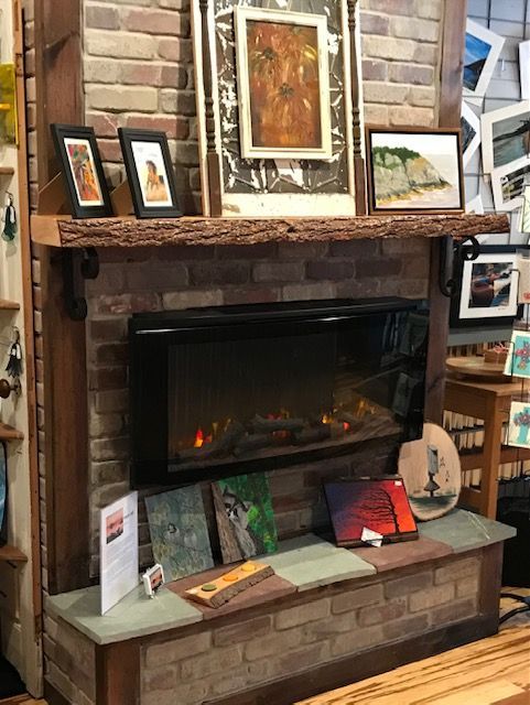 A fireplace with paintings on the mantle in a living room