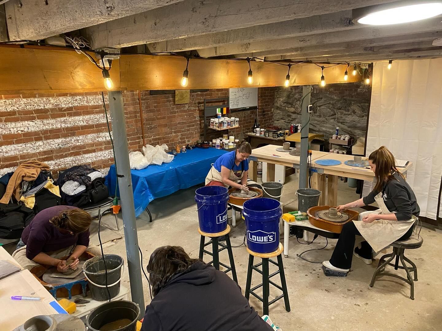 A group of people are working on a pottery wheel in a basement.