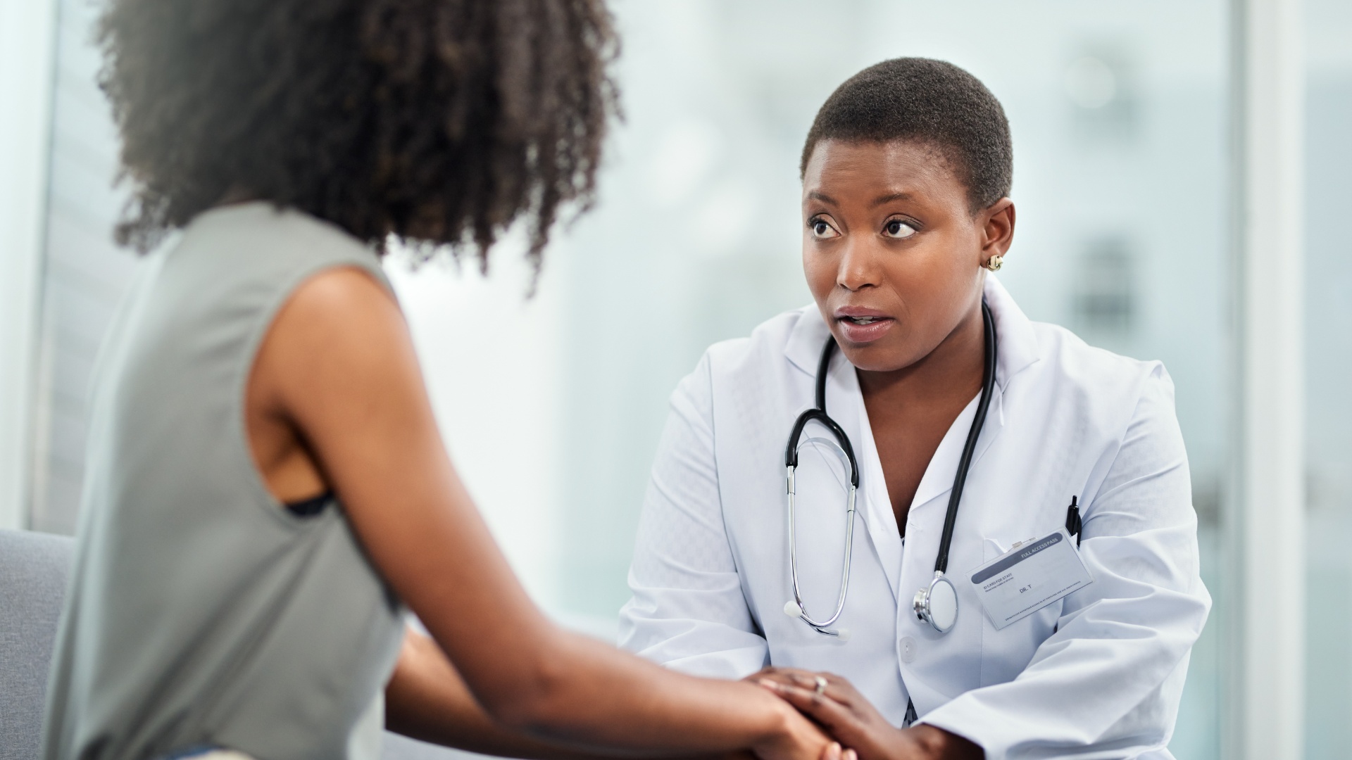 A doctor is holding a patient 's hand while talking to her.