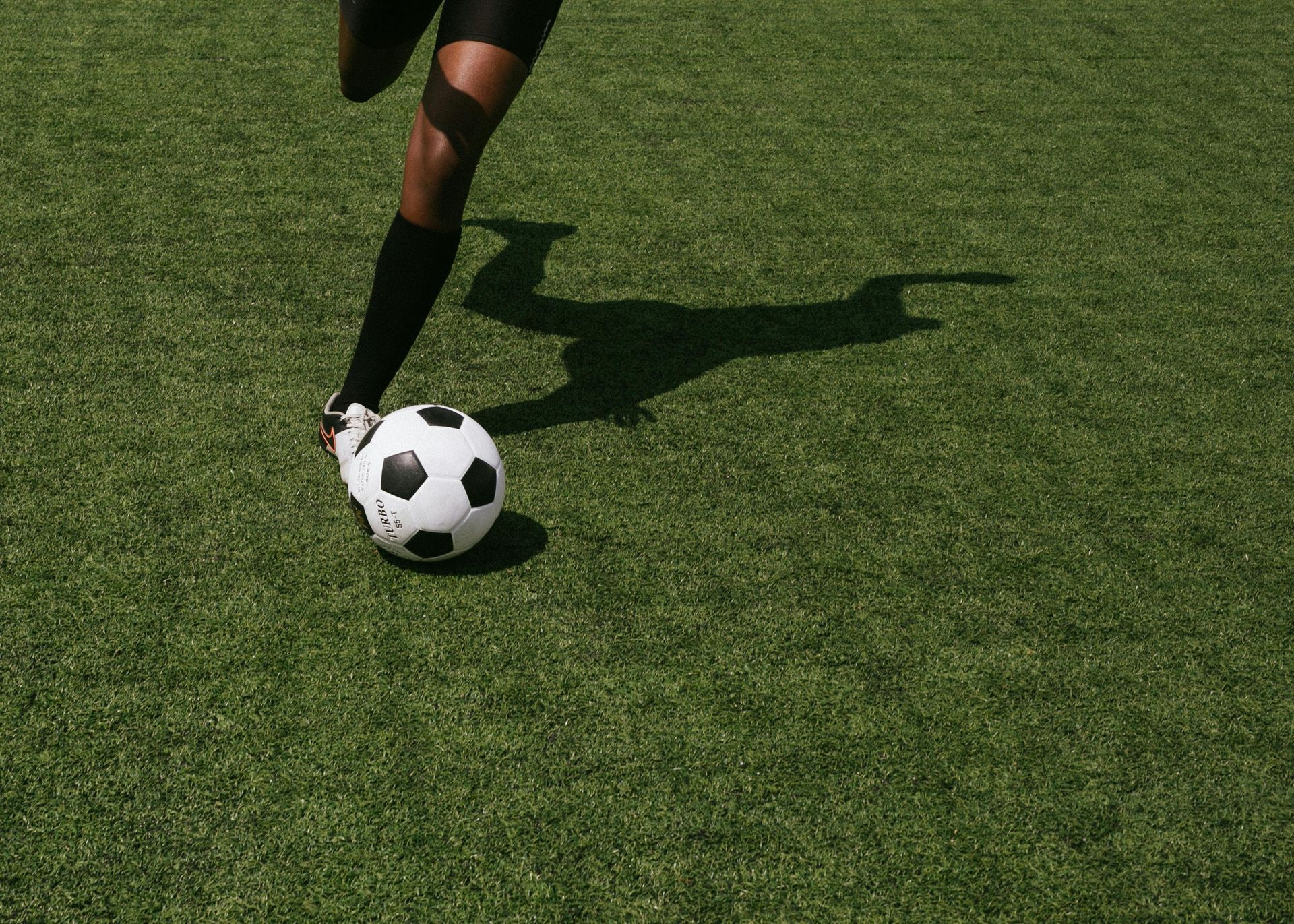 A person is kicking a soccer ball on a field.