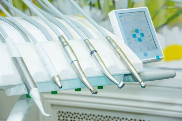 Dental tools: Handpieces and instruments mounted on a white dental unit with a digital screen.