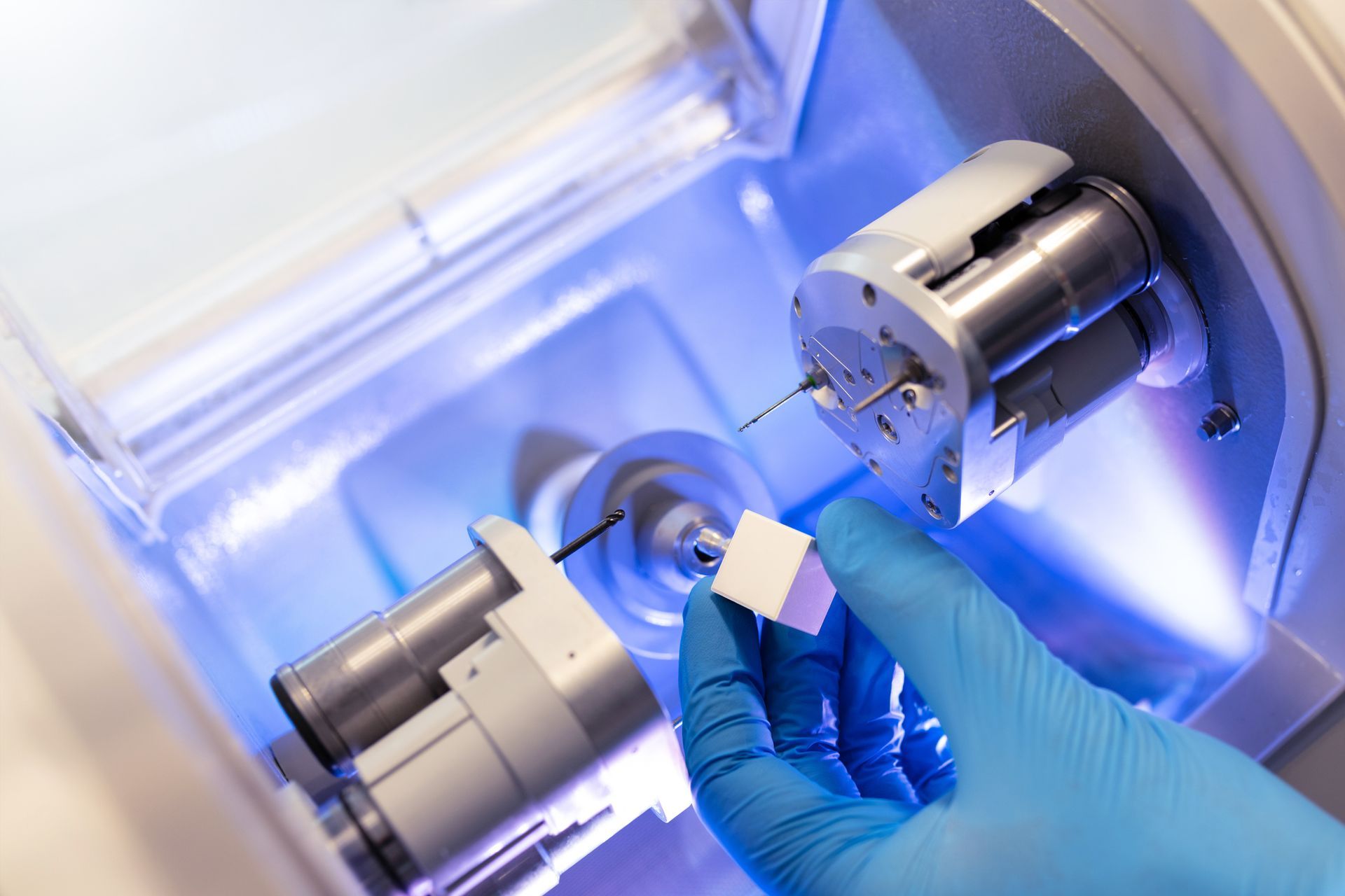 Dentist holding dental mold, pointing with probe at it, in blue-gloved hands. Patient facing, blurry in foreground. Dentist holding dental mold, pointing with probe at it, in blue-gloved hands. Patient facing, blurry in foreground.