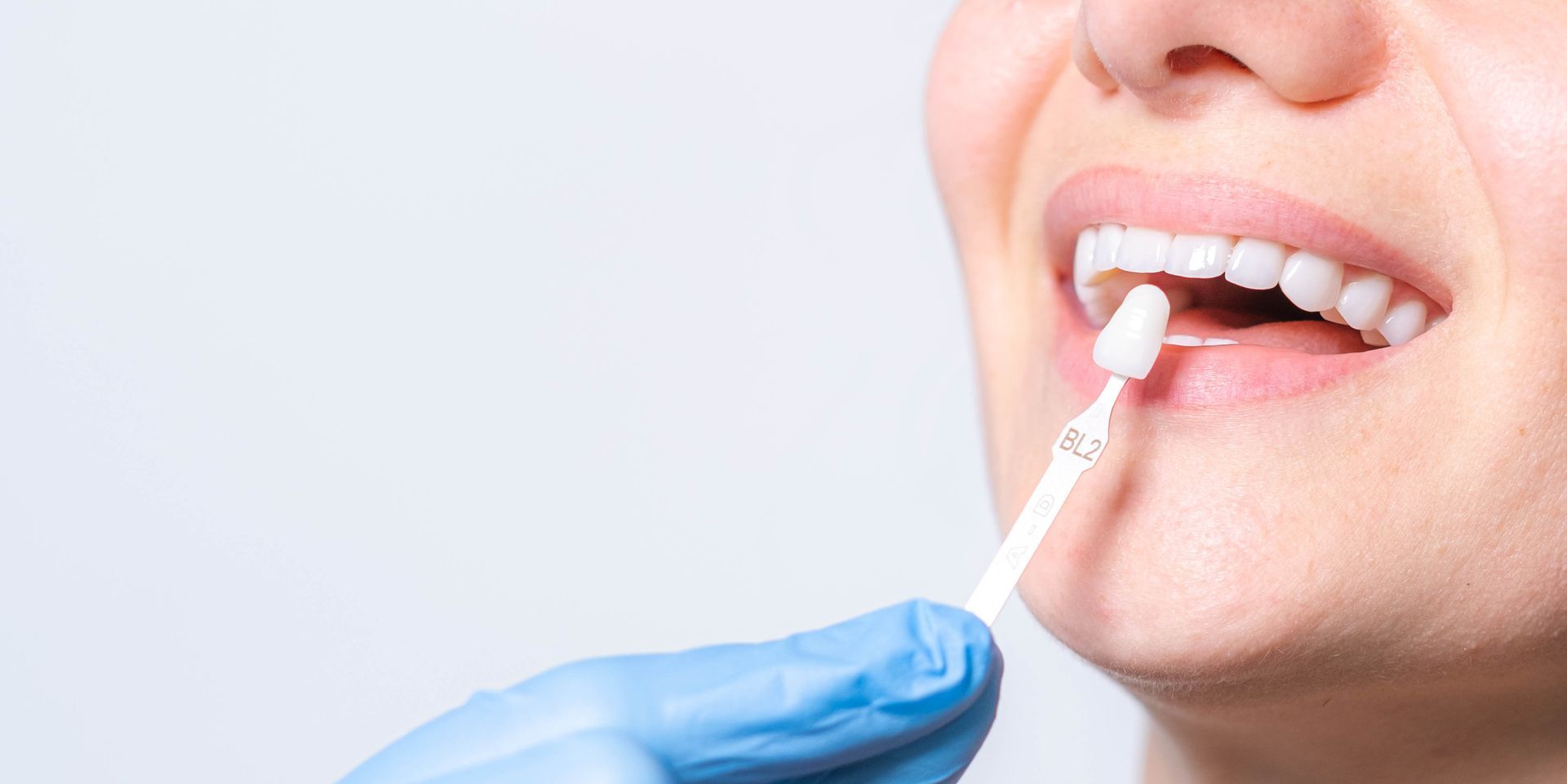 A person taking a swab test, with a blue-gloved hand holding the swab near the person's mouth. A person taking a swab test, with a blue-gloved hand holding the swab near the person's mouth.
