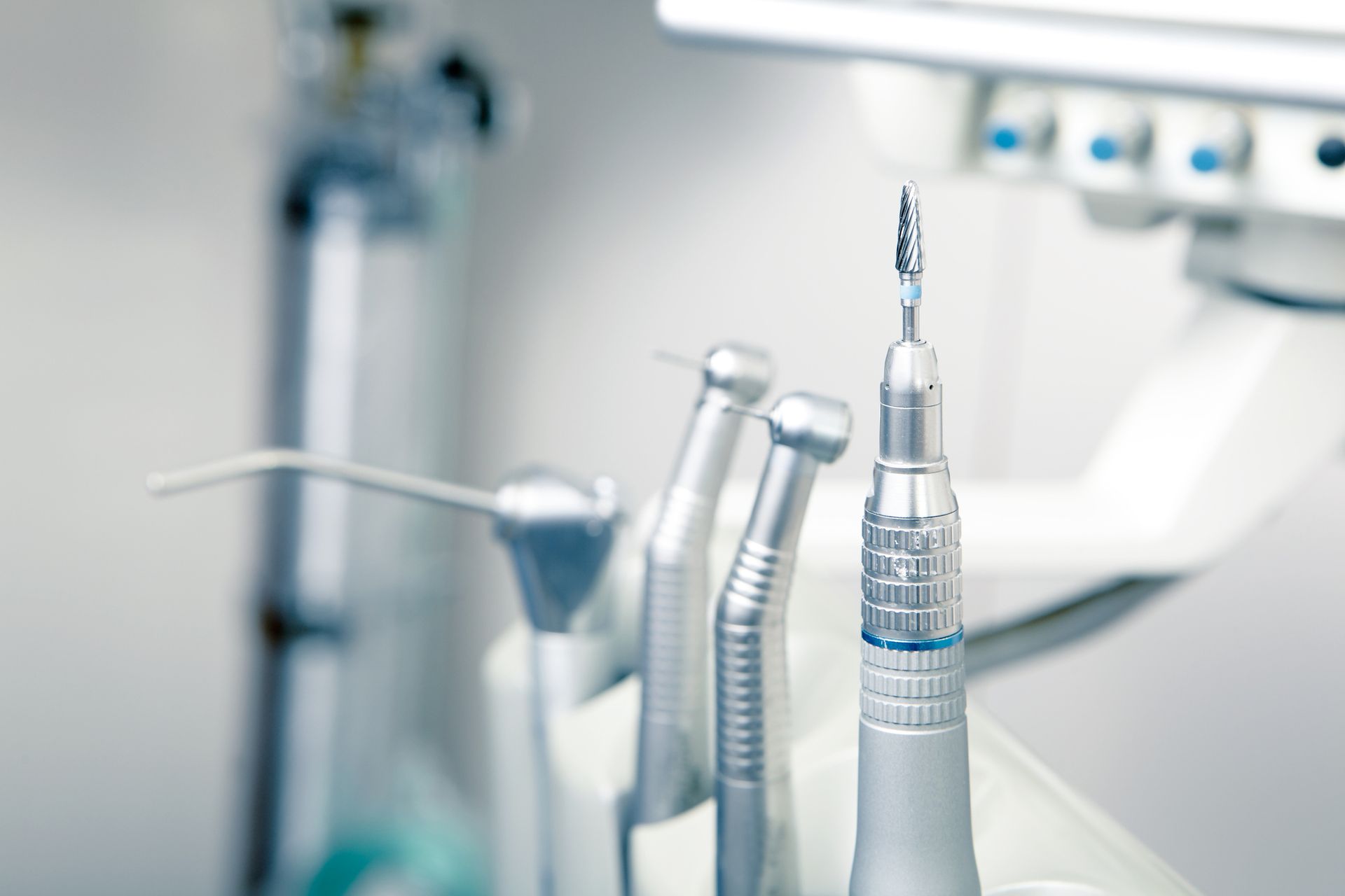 Dental tools: drill bit, air/water syringe, and other dental instruments in a clinical setting.