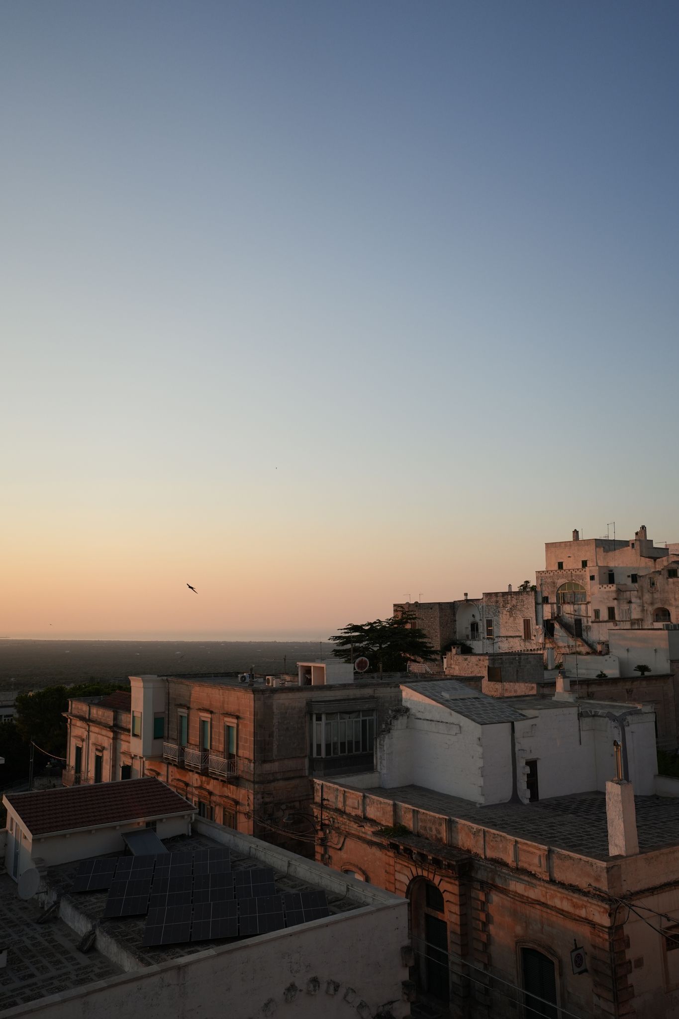 Sunset over a hillside town with terracotta rooftops and a pastel sky