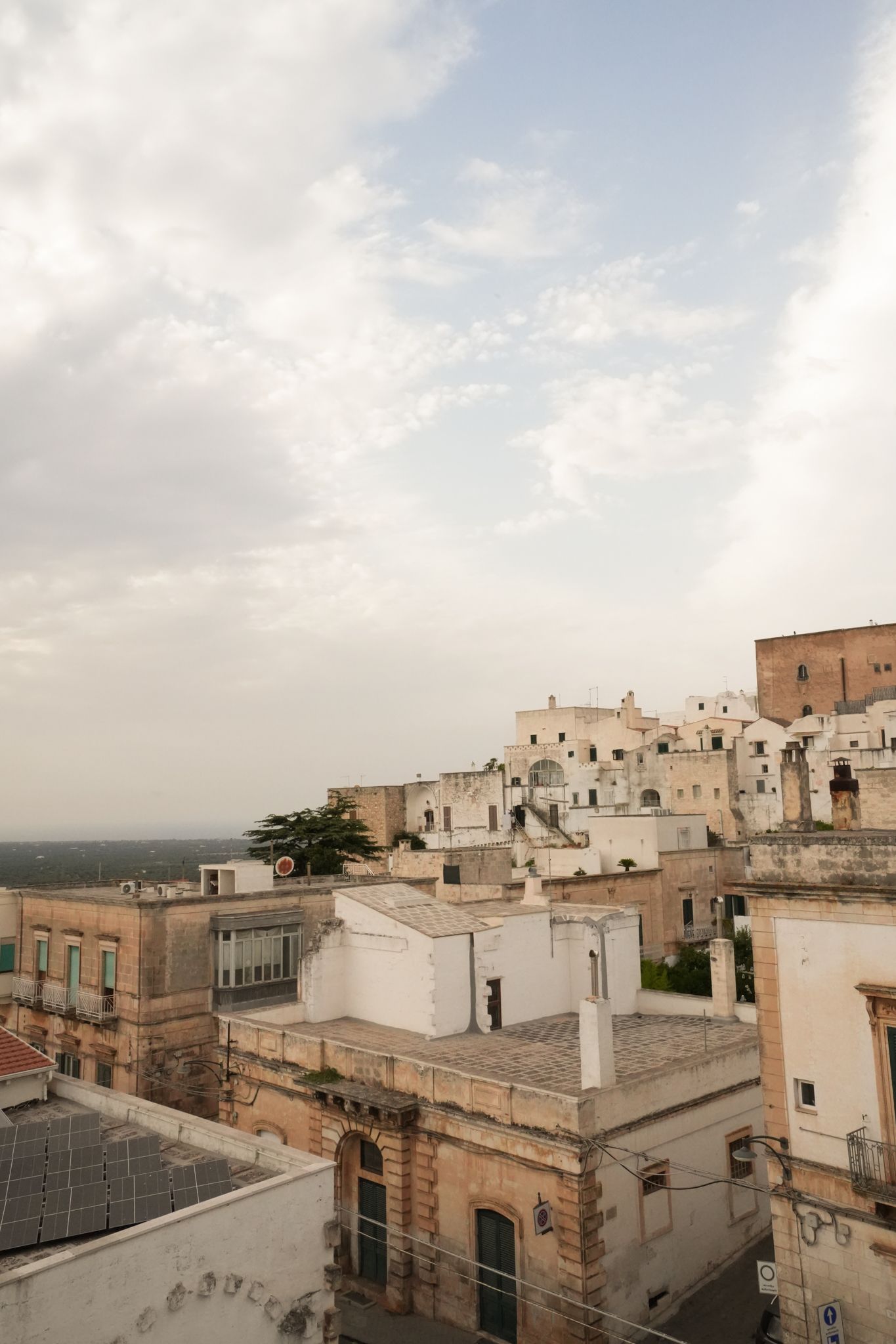 Hilltop town with white and tan buildings under a cloudy sky at sunset