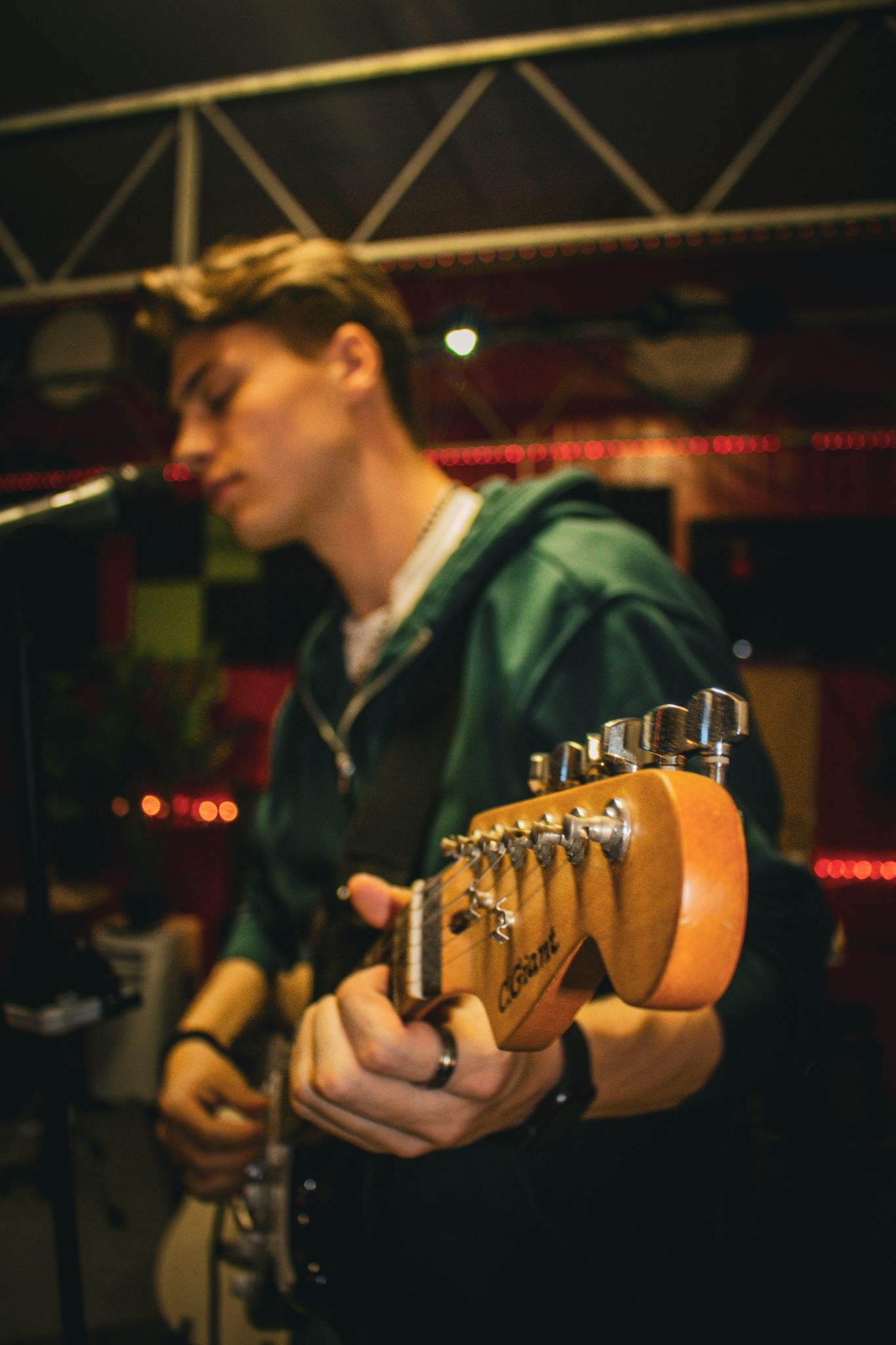 Een jongeman speelt elektrische gitaar voor een microfoon.