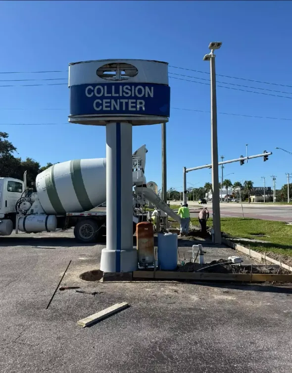 Concrete footing installation behind commercial sign base near outlining parking lot