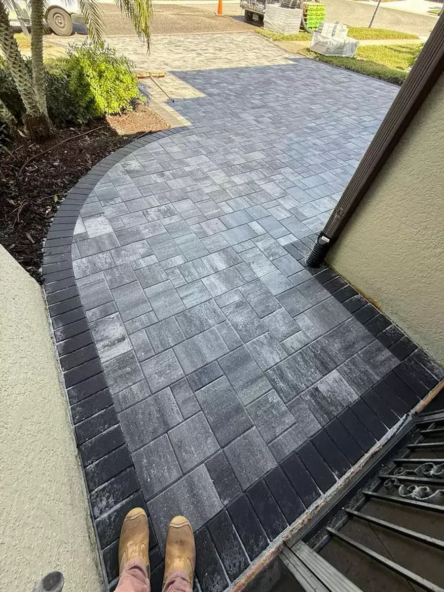 Curved concrete paver driveway with grey pavers and black outer edge