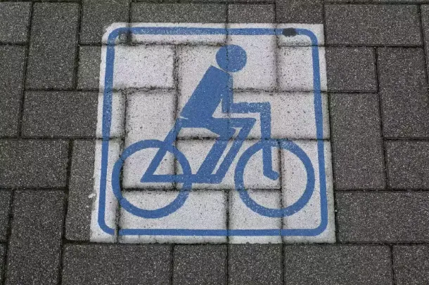 Blue bicycle symbol painted on gray concrete paver surface