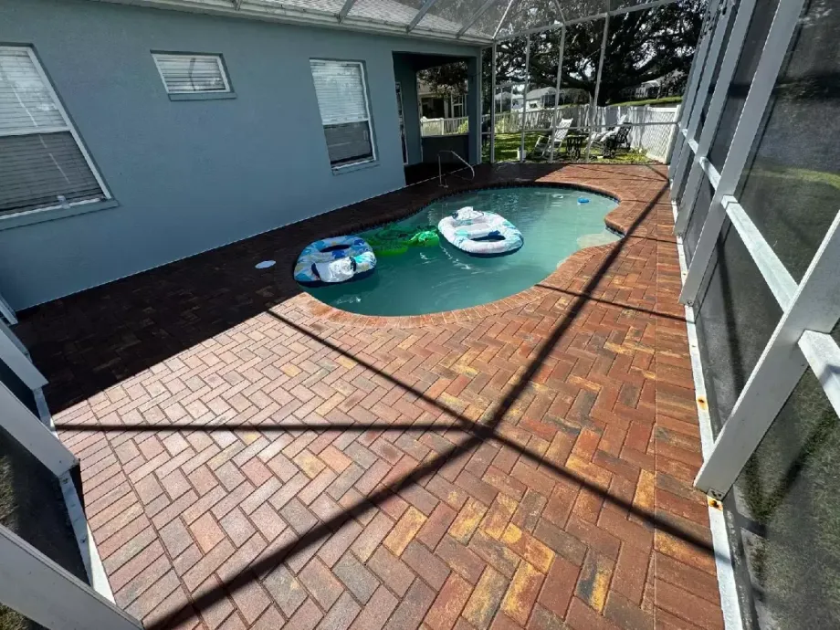 Brick paver pool deck surrounding screened residential pool