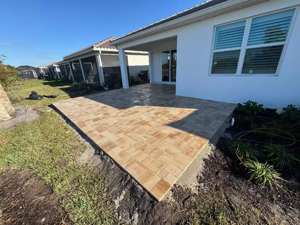 Rectangular tan concrete paver patio behind residential home