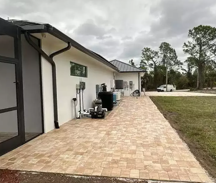 Tan concrete paver patio extension installed along side of residential home