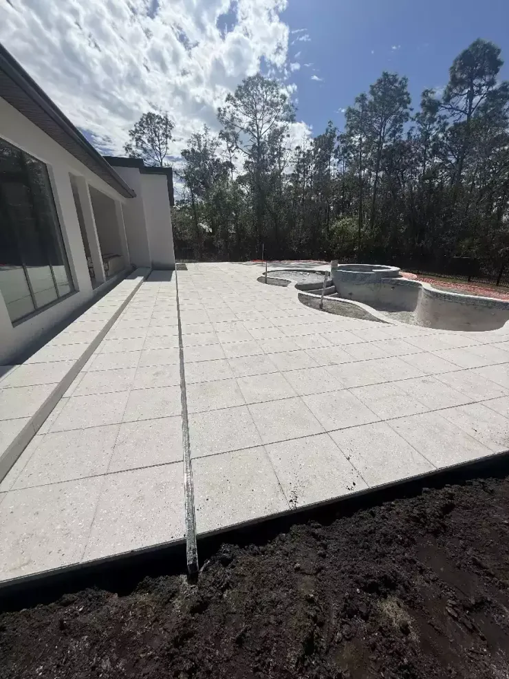 New large format paver pool patio installation behind residential home in Florida