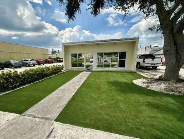 Commercial building entrance with artificial turf lawn and concrete walkway