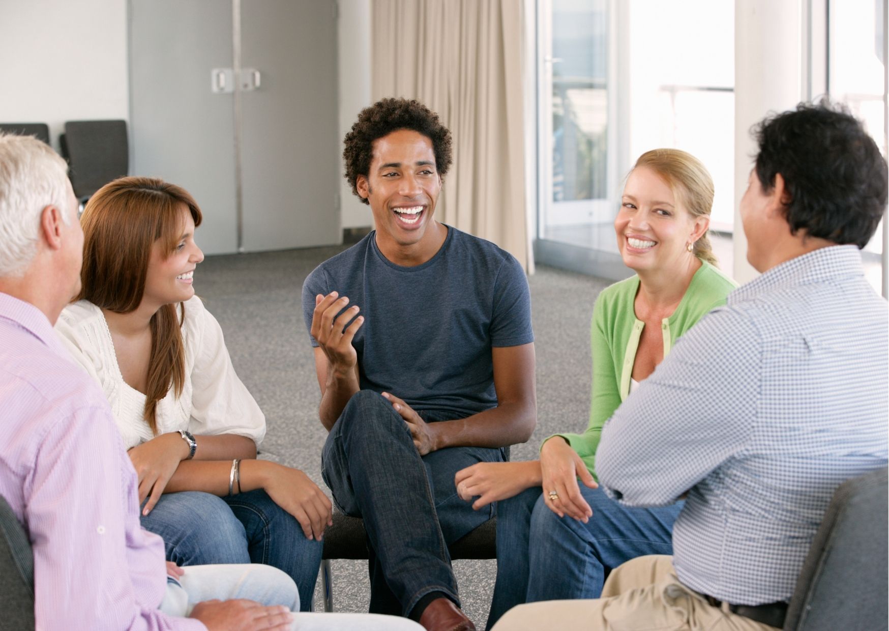 A doctor is writing on a clipboard while using a laptop computer.