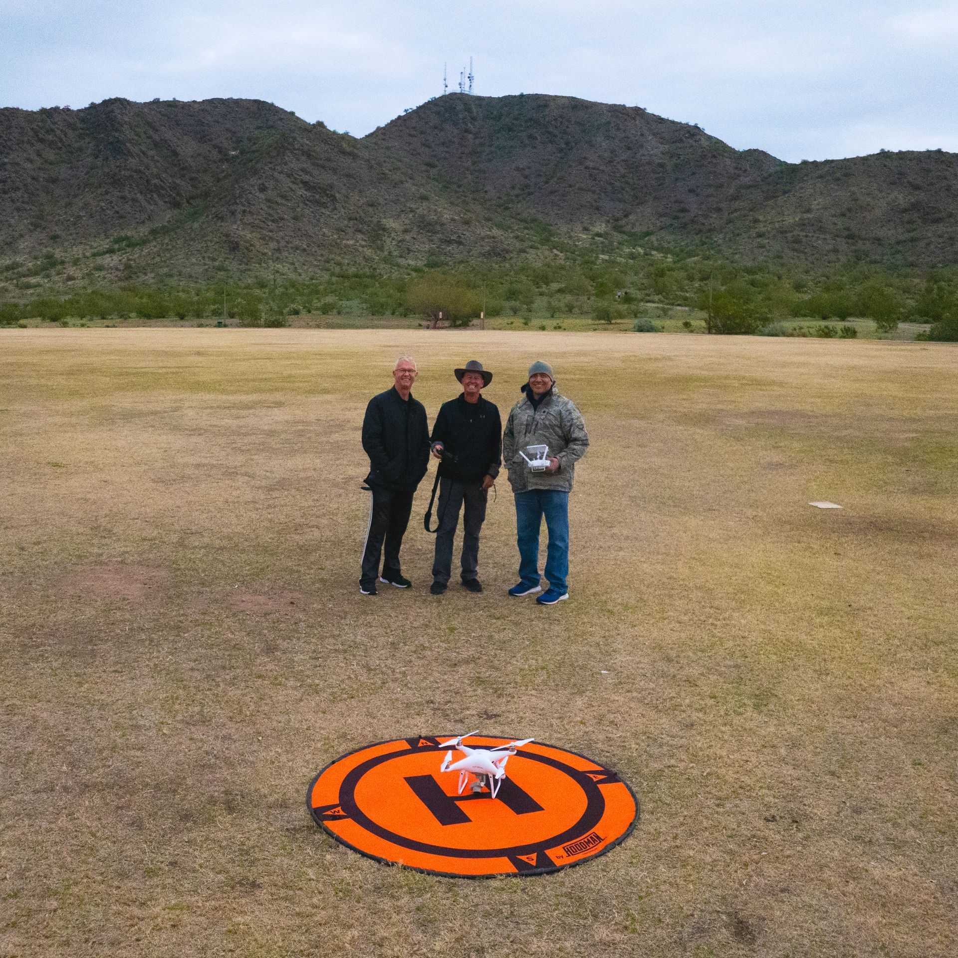 Three men are standing in a field with a drone Photo by Phoenix Drone Pros, Robert Biggs, 