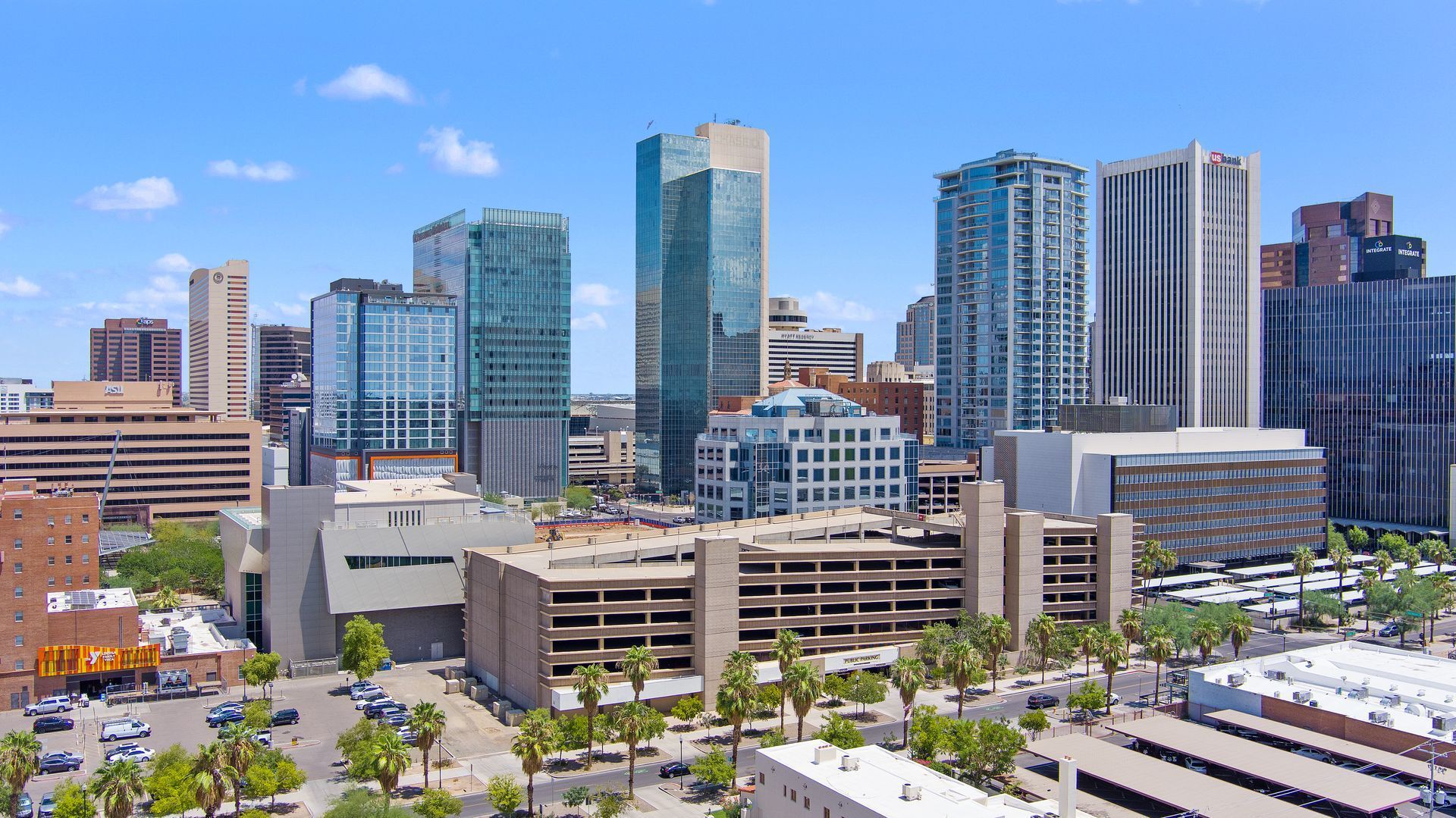 Photo by Phoenix Drone Pros, Robert Biggs, An aerial view of a city skyline with a parking garage in the foreground.