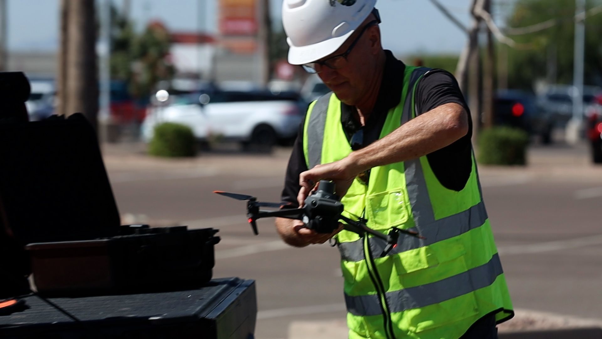 A man in a hard hat and safety vest is holding a drone. Photo by Phoenix Drone Pros, Robert Biggs