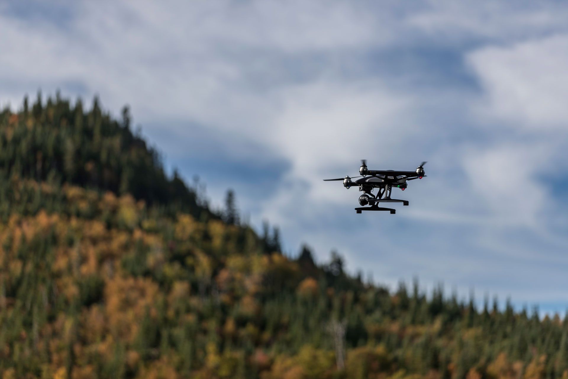 A drone is flying over a mountain with trees on it.