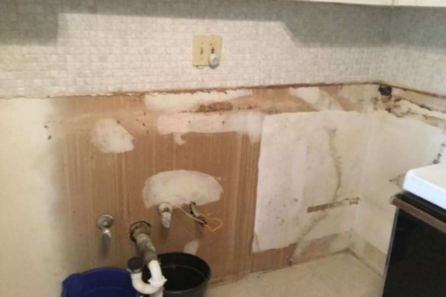 Corroded and deteriorated old pipes exposed after kitchen sink removal showing rust and mineral buildup