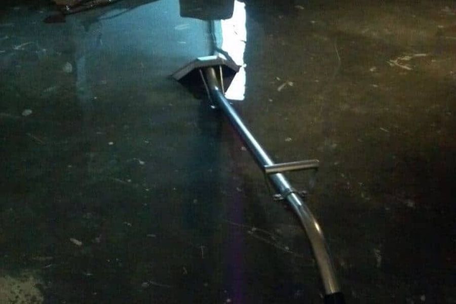 Professional water extraction equipment removing standing water from a flooded room