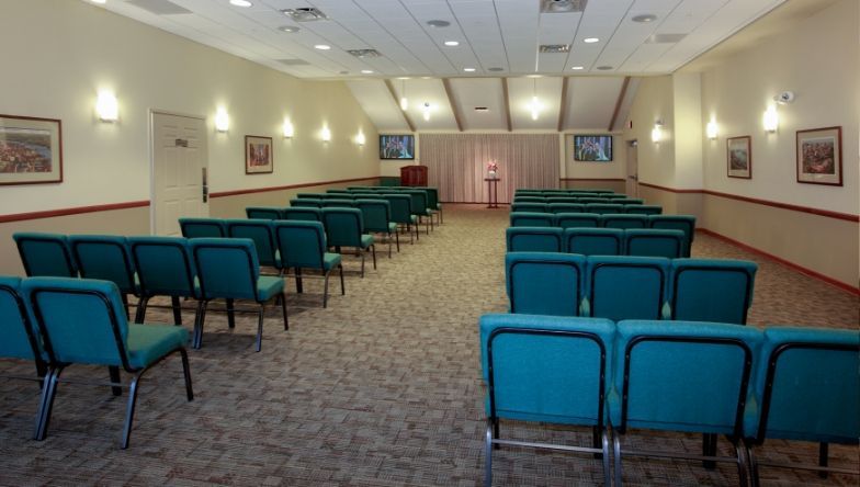 an empty auditorium with rows of seats and a coffin in the background .