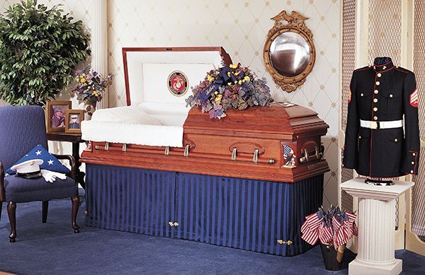 a coffin is sitting in a living room next to a mannequin in a marine uniform
