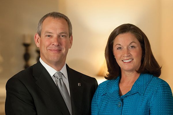 a man in a suit and tie and a woman in a blue shirt are posing for a picture .