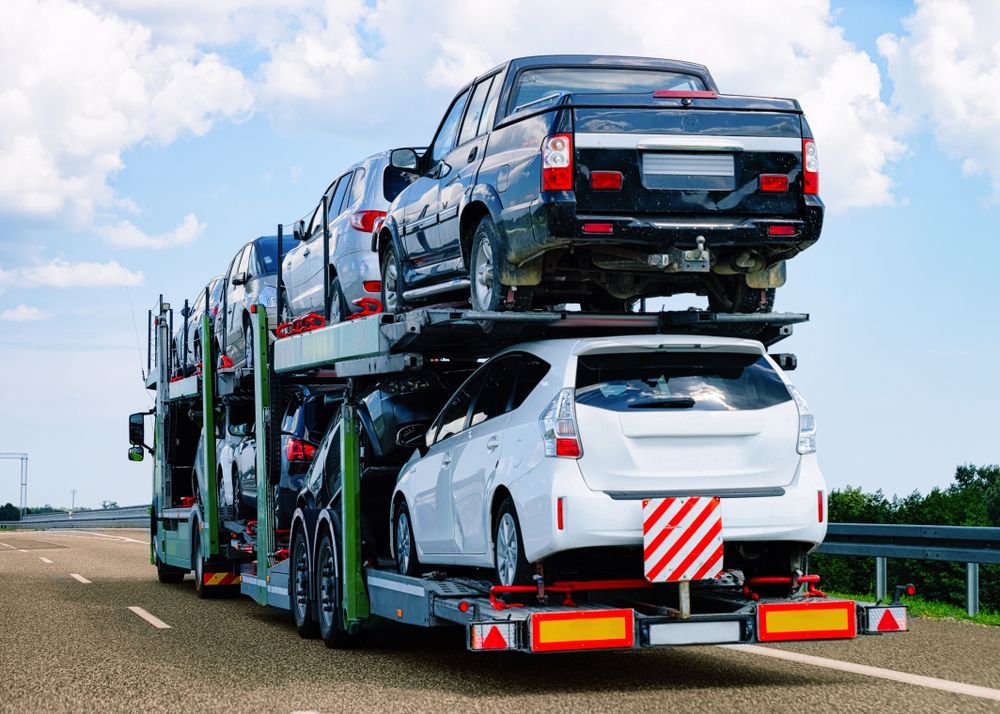 Car Carrier Truck Transporting Several Vehicles on a Highway Under a Blue Sky — Huntlys Heavy Equipment in Gracemere, QLD