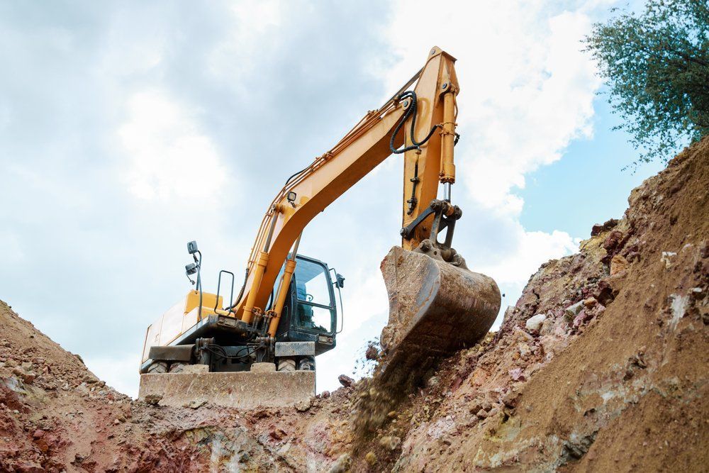 Yellow Excavator Digging in a Dirt Pit Under a Cloudy Sky — Huntlys Heavy Equipment in Gracemere, QLD