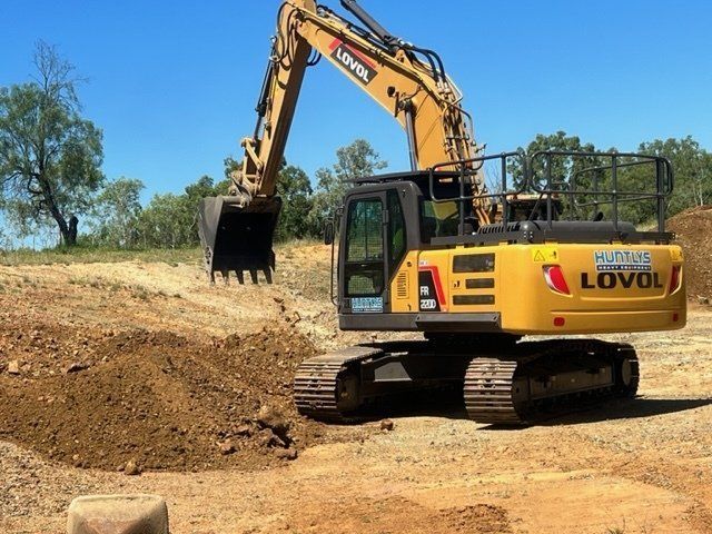 Yellow Lovol Excavator Digging Dirt at a Construction Site Under a Blue Sky — Huntlys Heavy Equipment in Gracemere, QLD