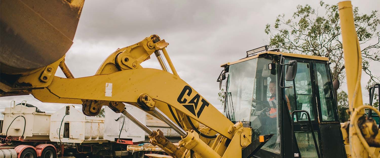 Yellow Cat Heavy Machinery, Overcast Sky, Working on a Construction Site — Huntlys Heavy Equipment in Gracemere, QLD