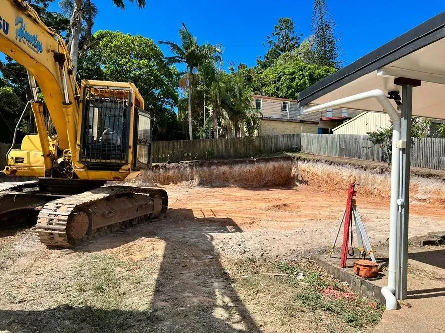 Yellow Excavator in a Construction Site, Digging a Large, Red-soiled Pit — Huntlys Heavy Equipment In Gracemere, QLD